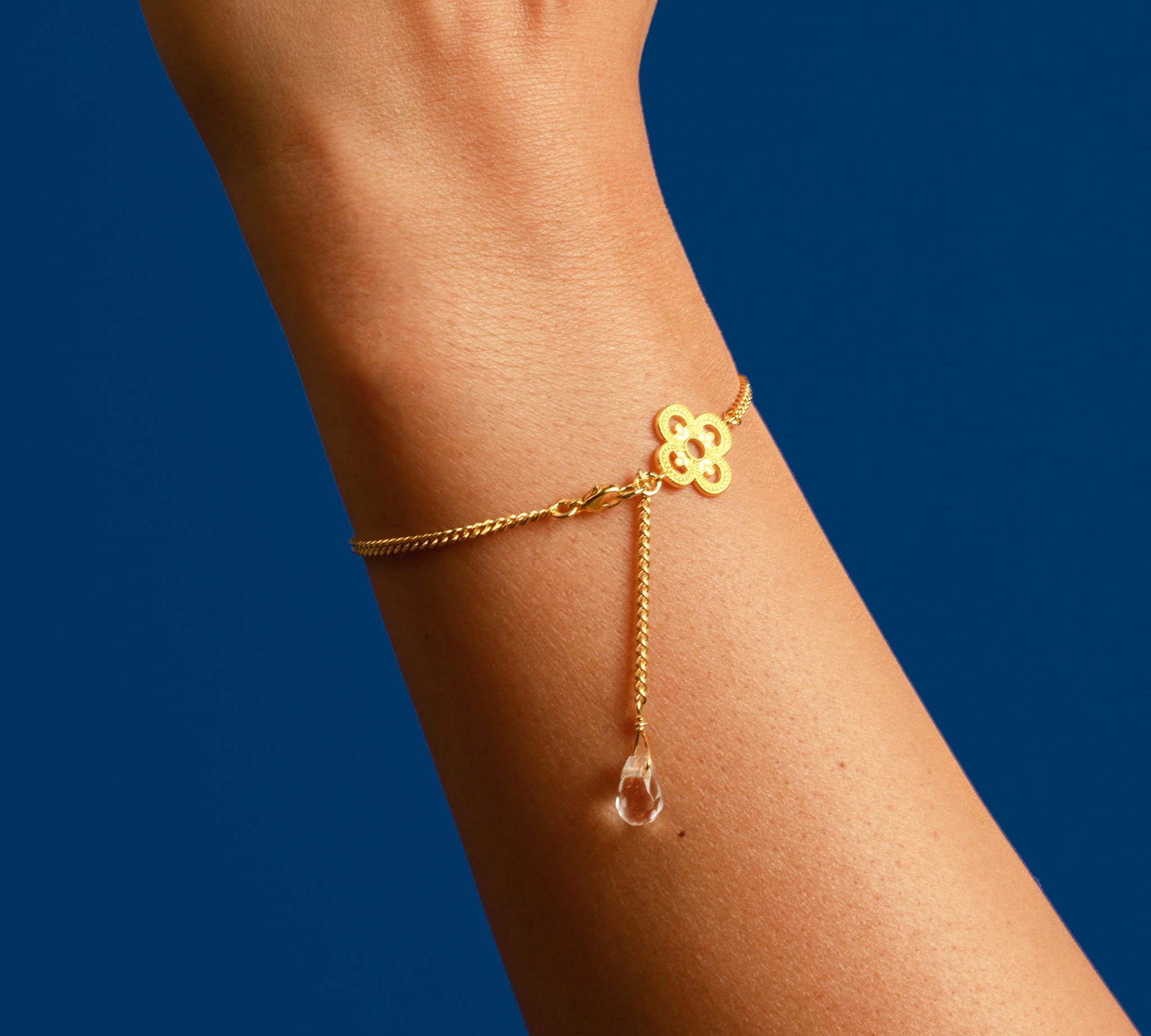 Frau trägt goldenes Kleeblatt Armband am Handgelenk.
