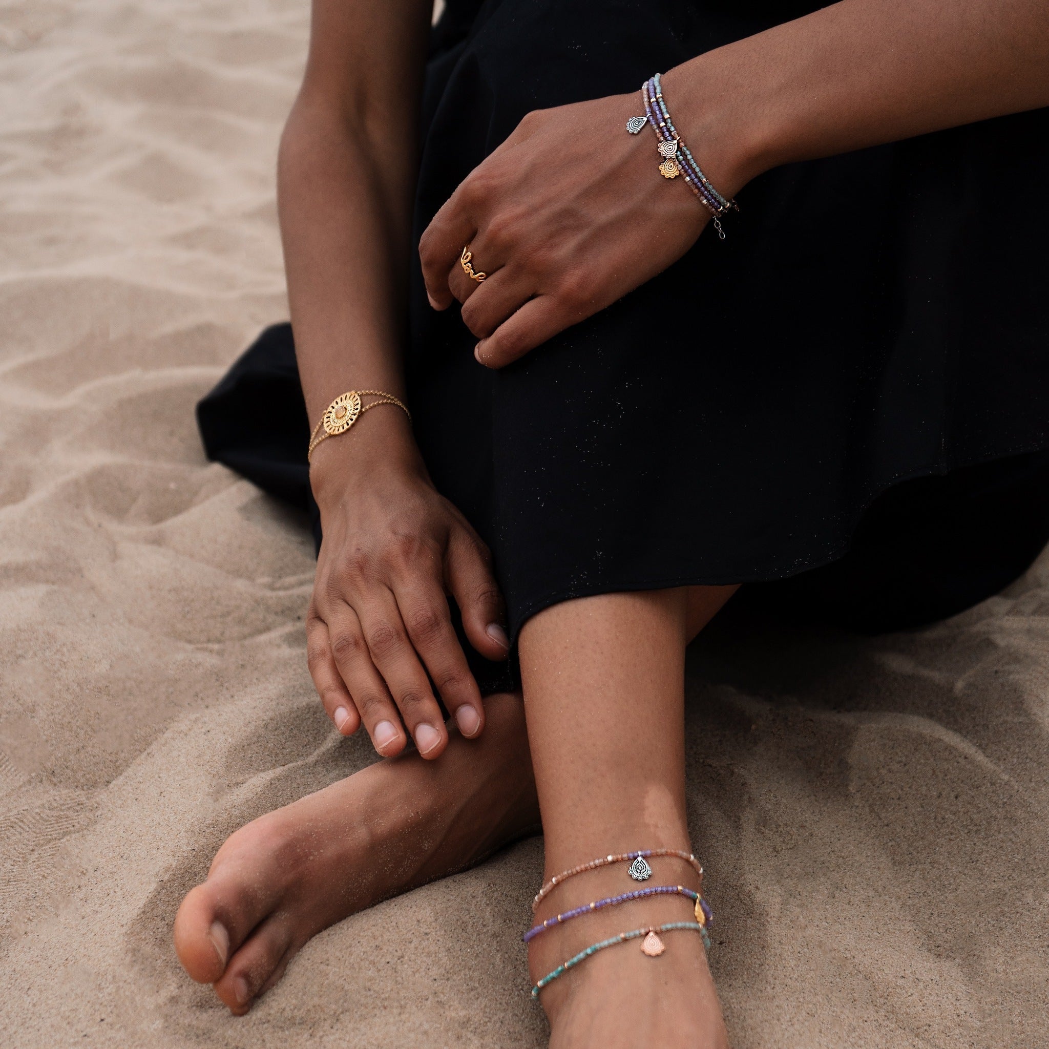 Fußkettchen aus Achat Edelsteinen und Sonnen Anhängern an Frau im Sand