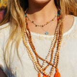 Mala Kette mit sieben Chakra Edelsteinen und orangefarbener Quaste.