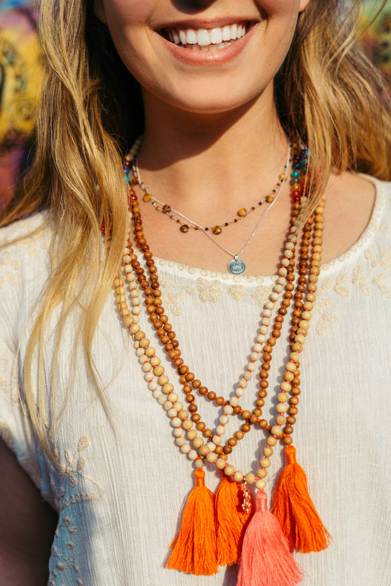 Mala Kette mit sieben Chakra Edelsteinen und orangefarbener Quaste.