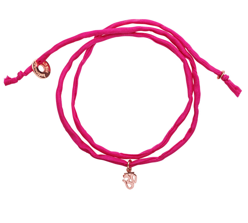 Pinkes Seidenarmband mit roségoldenem OM Anhänger als Wickelarmband.