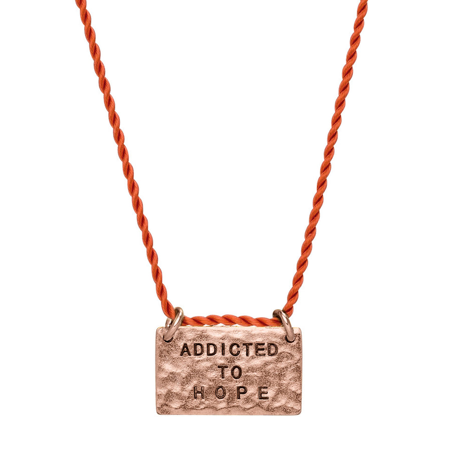 Kette mit Glücksbringer Anhänger aus rotem Kordelband und rosegoldenem Anhänger.